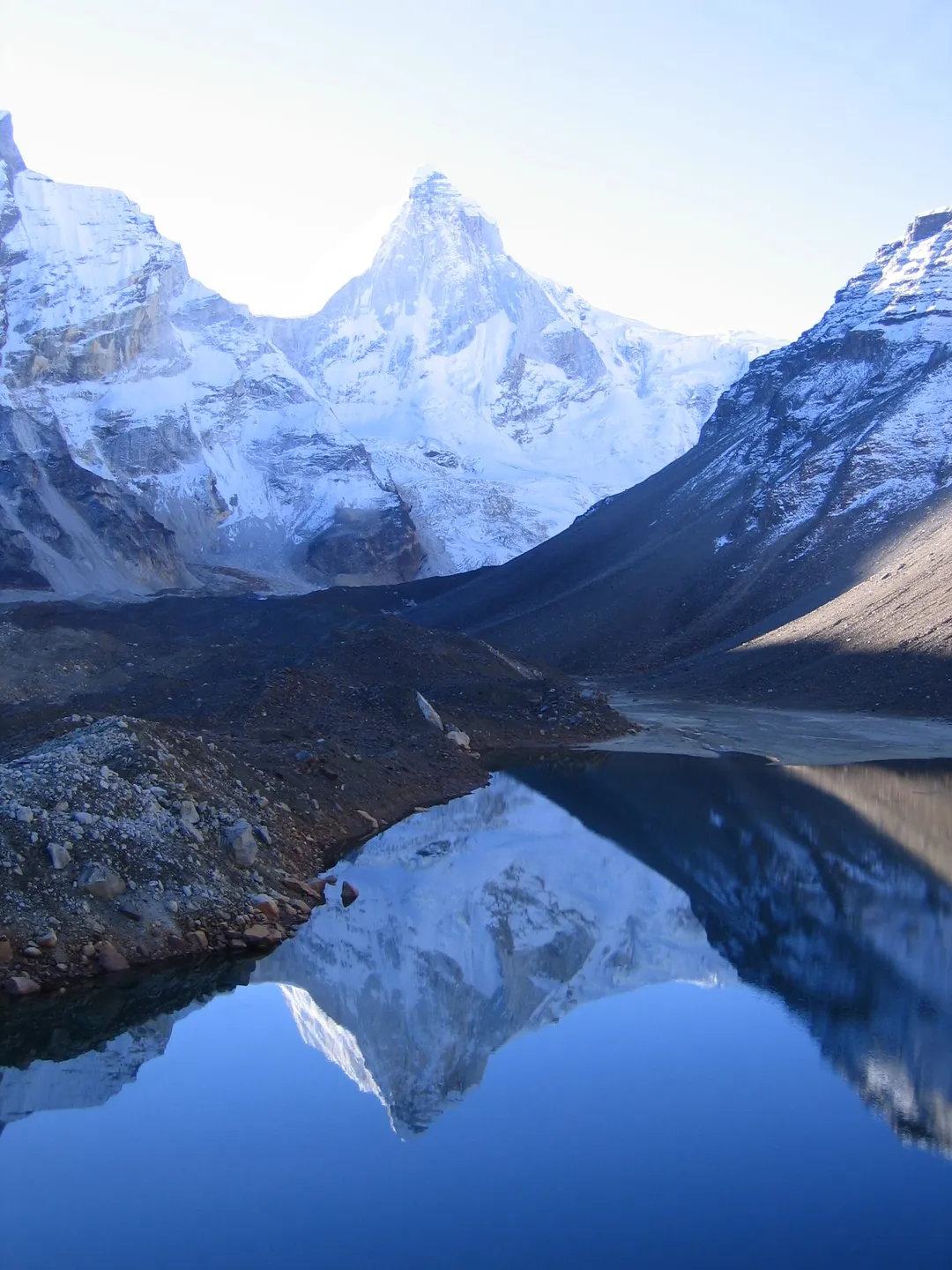 Kedar Tal at first light, Thalay Sagar reflected in the still water with moraine along the near shore