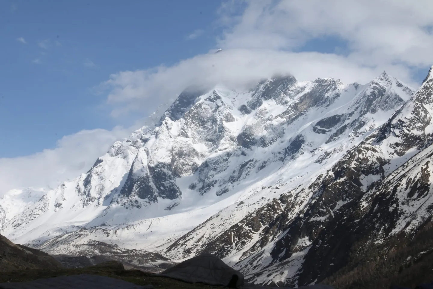 Swargarohini — a high snow-and-rock face with cloud streaming off the summit and glacier slopes falling away below — photographed from the neighbouring Har Ki Dun valley, not from Dev Kyara. It is one of the peaks the meadow looks out on.